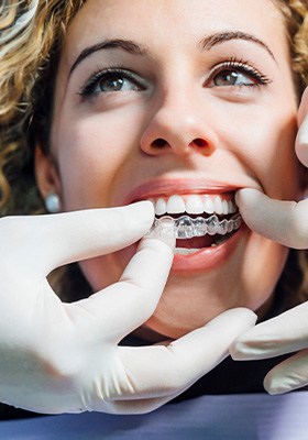 A dentist gently placing a woman’s Invisalign tray
