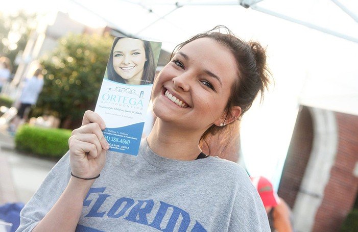 Woman smiling next to Ortega Orthodontics brochure with her picture